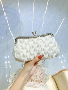 Detail of white pleated satin clutch with crystal-encrusted silver metal frame and clasp