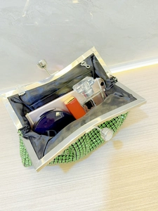 Detail showing the green rhinestone clutch bag interior with phone and cosmetics