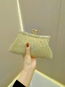 Close-up of a gold evening clutch bag featuring a crystal-encrusted hardshell and metal clasp