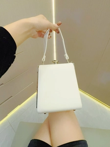 Draufsicht einer weißen kastenförmigen Abendtasche mit Metallverschluss und Standfüßen