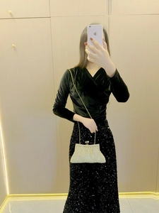 Detailed view of luxury gold rhinestone clutch bag paired with a velvet evening outfit