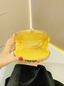Details einer goldenen Abendtasche mit Strass-Kugelverschluss und gelbem Satin-Innenfutter