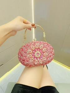 Nahaufnahme der rosa Strass-Abendtasche mit kunstvollem Goldgriff und floralem Musterdesign