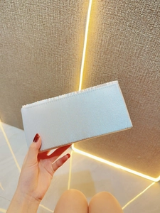Detail of light blue satin evening clutch bag with elegant pleated edges and metallic luster