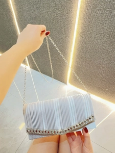 Detail of silver pleated evening clutch bag with sparkling rhinestones and metal chain