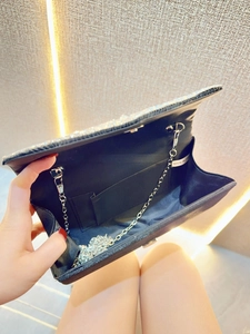 Detail of evening clutch interior with silver chain strap and black fabric lining
