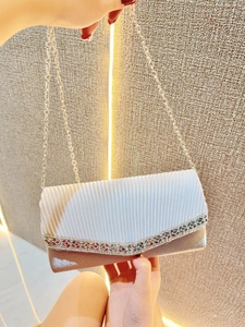 Detailed view of a pleated silver evening clutch with sparkling rhinestone trim and chain