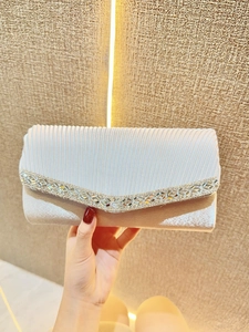 Detail of silver pleated satin evening clutch with sparkling V-shaped crystal accents