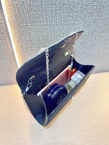Internal storage detail of black chain evening bag showing space for phone and makeup