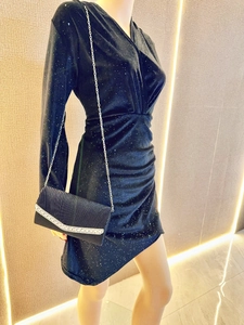 Detail of elegant black pleated clutch bag with rhinestone trim and silver chain strap