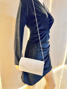 Detailed close-up of cream evening clutch bag with pleated satin and silver rhinestone trim