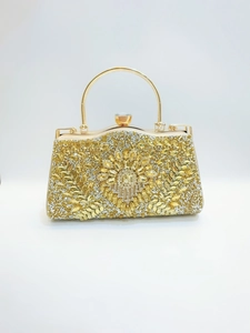 Gros plan d'une pochette de soirée dorée avec motifs floraux en strass et fermoir cristal