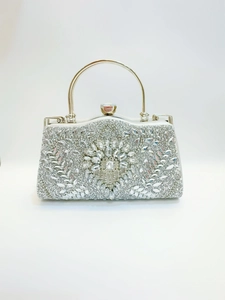 Détail macro du motif floral en strass radial sur une pochette de soirée de luxe argentée