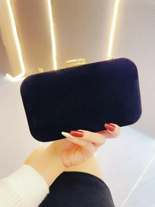 Detail of black velvet evening clutch featuring a sparkling diamond-encrusted metal clasp