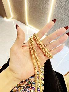 Detailed macro shot of a glossy gold metal braided chain with a spiral twisted structure