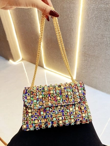 Close-up of a luxury flap bag with colorful crystals and a gold chain strap