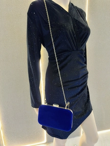 Detail of royal blue velvet evening clutch with gold metal frame and chain strap on black dress