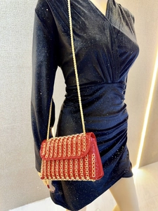 Detail of red bridal evening bag featuring gold metal accents and sparkling glitter finish