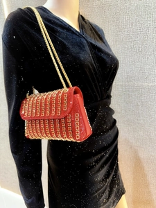 Detail of red bridal evening bag with gold sequins and dual chain strap on model