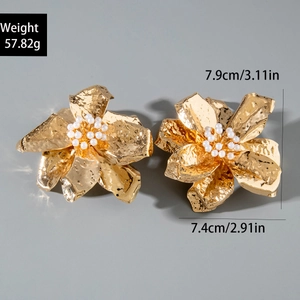 Detailed macro view of large golden petal earrings with pearl center and hammered texture