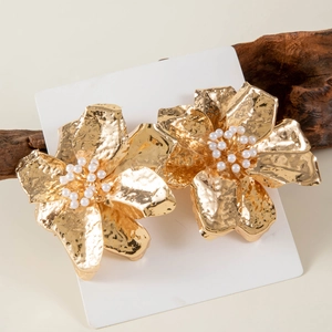 Detail of golden flower earrings with hammered metal texture and white pearls