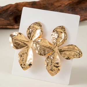 Detailed view of gold flower earrings with hammered texture and natural wood background