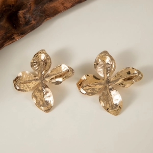 Macro detail of golden hammered flower earrings featuring refined pearl-like textures