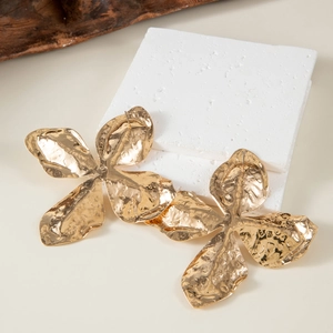 Detailed macro view of large golden flower earrings with textured hammered finish and pearls