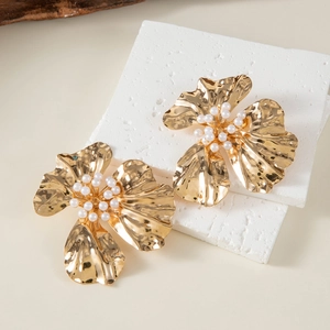 Detail of golden flower earrings with pleated metal petals and tiny pearl center