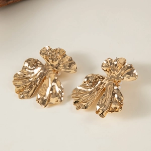 Artistic gold flower earrings with wrinkled texture and pearl accents on beige backdrop