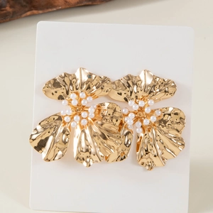Detail of golden pleated flower earrings with white pearl centers on white card