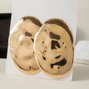 Detail of large gold oval earrings with hammered texture and minimalist pearl accents