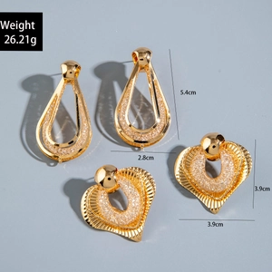 Detail view of gold earrings featuring teardrop and heart shapes with textured finishes