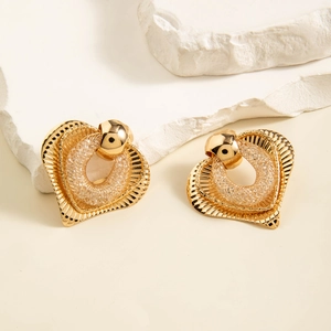 Macro view of gold heart-shaped earrings with textured patterns and translucent center detail