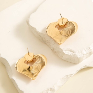 Macro detail of heart earrings with radial texture and hollow design on a stone base
