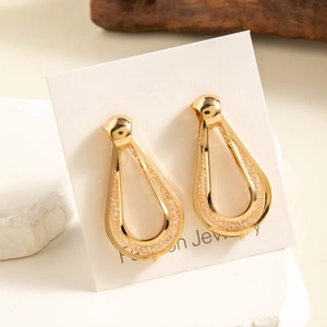 Detail of drop-shaped gold earrings featuring intricate woven metal mesh textures