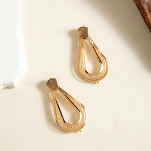 Macro view of gold-plated teardrop earrings featuring intricate woven mesh textures