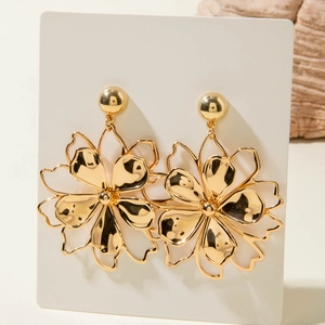 Close-up of golden geometric flower earrings with hollow petals and a pearl detail