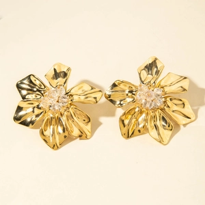 Detailed close-up of golden flower earrings with pleated petals and crystal centers