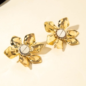 Detailed close-up showing the metallic hammered texture of large golden flower earrings