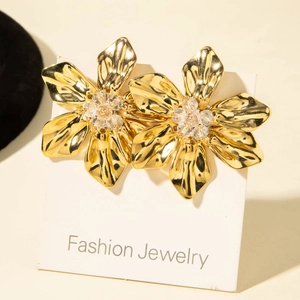 Detail shot of golden flower earrings with central crystal on fashion jewelry card