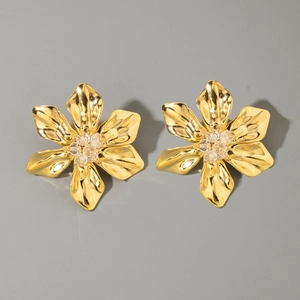 Close-up of golden flower earrings featuring textured petals and crystal cluster centers