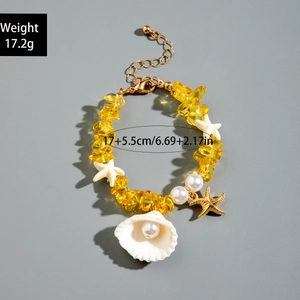 Détail d'un bracelet en coquillages avec breloques étoile de mer et chaîne dorée