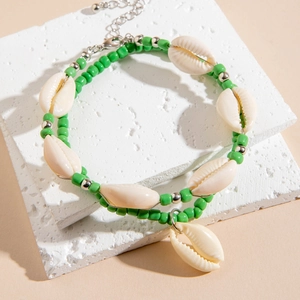 Vue détaillée de bracelets de cheville en perles vertes avec coquillages sur pierre