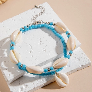 Détail de la chevillère en perles bleues et coquillage naturel sur socle blanc