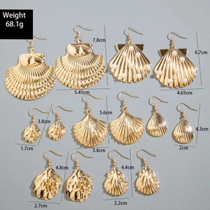 Détail de boucles d'oreilles bohèmes en coquillage doré avec perles et formes d'éventail