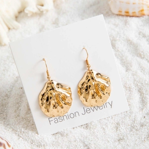 Vue détaillée de boucles d'oreilles bohèmes en forme de pétoncle doré avec perles