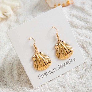 Détail de boucles d'oreilles bohèmes en forme de coquillage doré avec perles