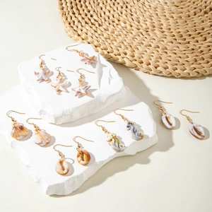 Marine summer beach earrings set with starfish and shell charms on stone display