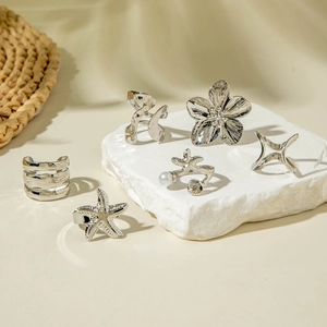 Détail d'un ensemble de bagues en alliage argenté avec perles, fleurs et étoiles de mer